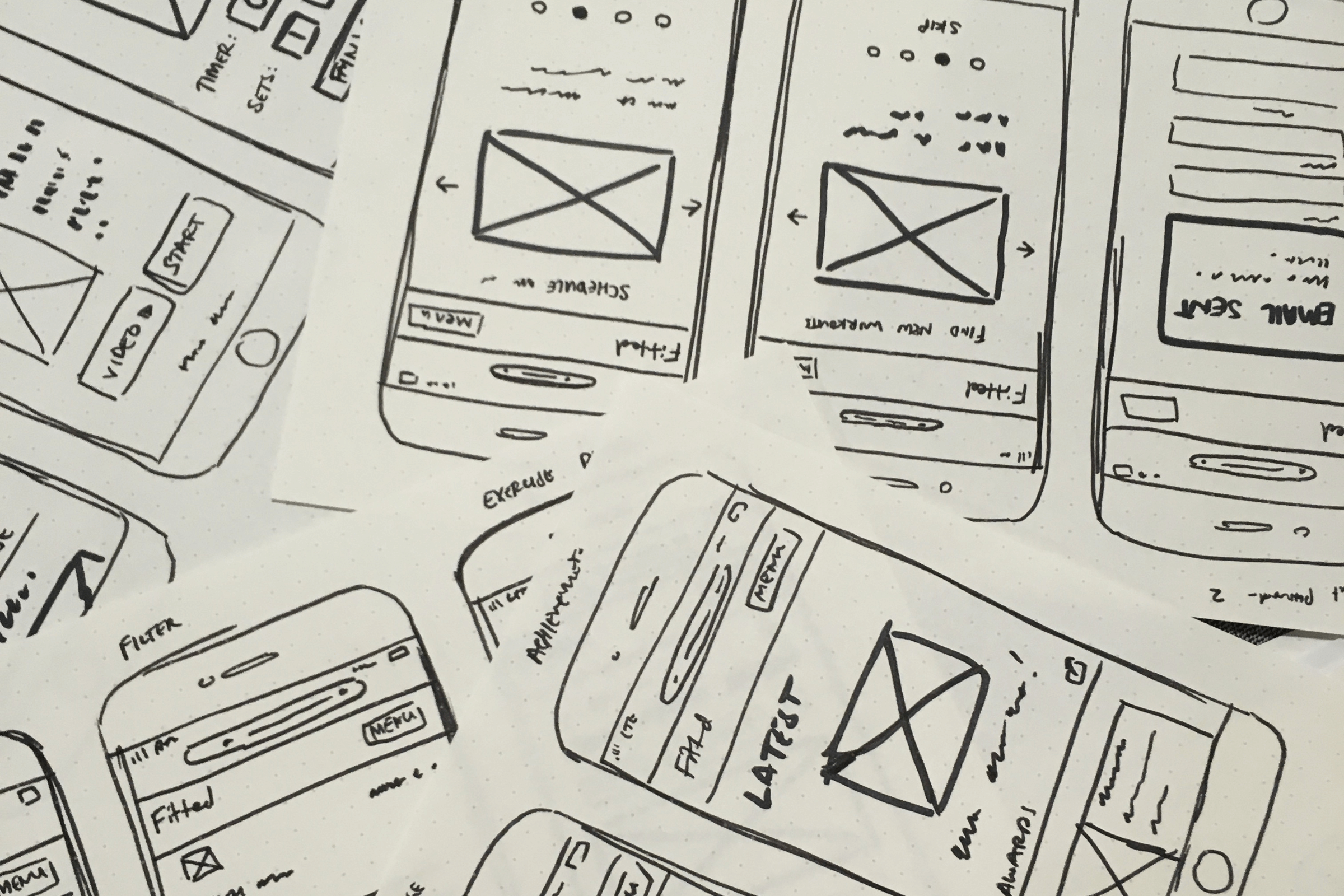 Many low-fidelity wireframes for Fitted scattered across a desk.